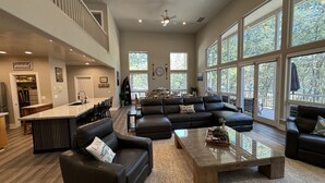 A spacious living room with a large sectional sofa, a coffee table, and a kitchen area with a bar. - Large Lakefront Paradise, 4000+ Sq Feet, Kayaks (Lakehead)