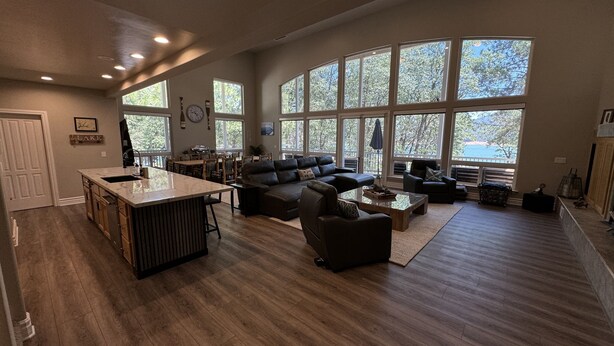 A spacious living area with a large window, a kitchen island, and a seating area with a sofa and chairs. - Large Lakefront Paradise, 4000+ Sq Feet, Kayaks (Lakehead)