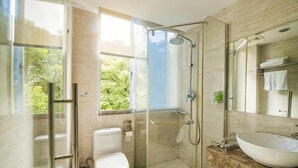 Un baño moderno con cabina de ducha de vidrio, inodoro y lavamanos grande.