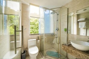 Un baño moderno con cabina de ducha de vidrio, inodoro y lavamanos grande.