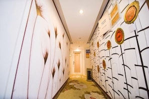 Un couloir aux murs ornés de motifs et dont le sol est recouvert d’une moquette.