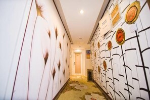 A hallway with patterned walls, a carpeted floor, and a door at the end.