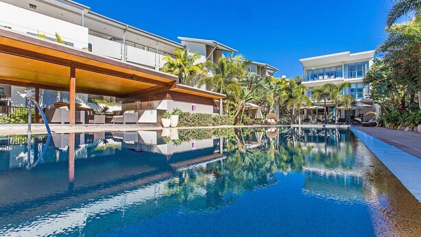 Ein modernes Hotel mit Schwimmbad, Außenbereich und üppiger Bepflanzung.
