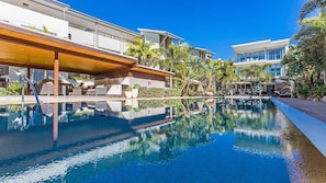 Un hôtel moderne doté d’une piscine, d’un espace extérieur aménagé et d’une végétation luxuriante.