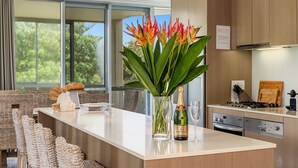 Eine moderne Küche mit einer großen Kochinsel, einer Champagnerflasche und einer Blumenvase.