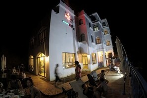 A building with multiple levels, outdoor seating, and a well-lit entrance.