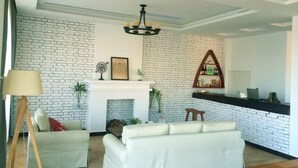 A living room with a white brick wall, a fireplace, a chandelier, and a bar area. - Shensi Gouqi Island Mr.Tang's Private Garden Inn (Shengsi)