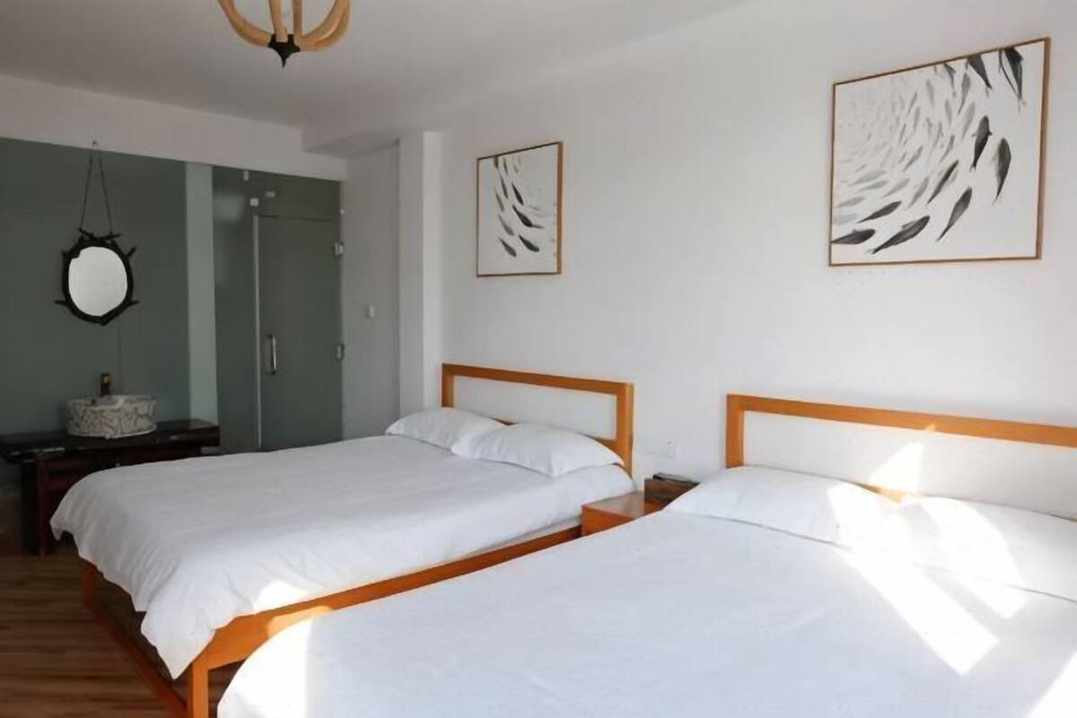 Ein Schlafzimmer mit zwei Betten, einem Spiegel und Bildern an den Wänden.