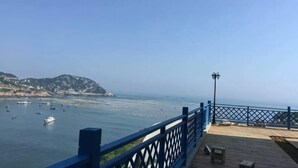 A coastal view from a wooden deck with a blue railing, overlooking calm waters and distant hills. - Shensi Gouqi Island Mr.Tang's Private Garden Inn (Shengsi)