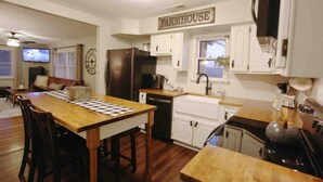 Una cocina con armarios de madera, un cartel rústico, un refrigerador, un microondas y una mesa de comedor con sillas.