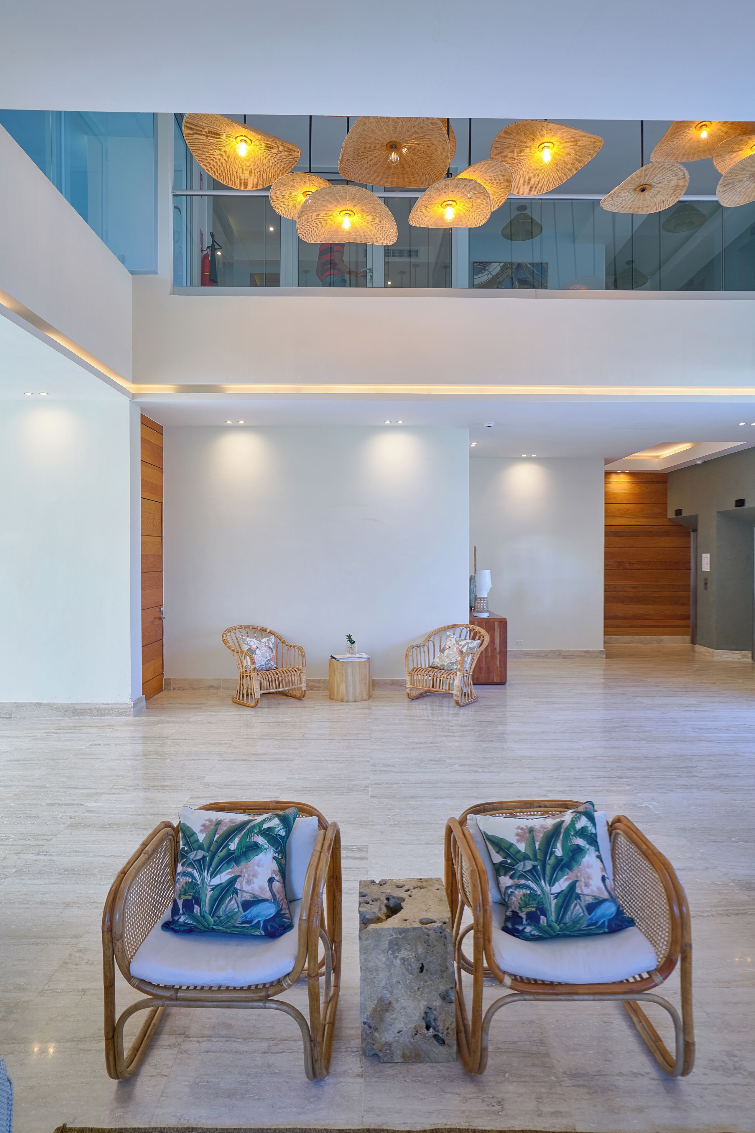 Um hall amplo com duas cadeiras de vime, uma mesinha lateral e um armário de madeira.