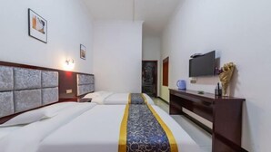 Ein Hotelzimmer mit einem Bett, einem Schreibtisch, einem Fernseher und einem an der Wand befestigten Fernseher.