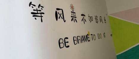 A wall with a quote in Chinese characters and its English translation 'BE BRAVE TO DO IT'.
