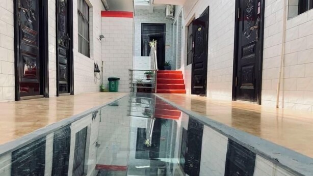 Ein Hotelgang mit spiegelndem Boden, schwarzen Türen und einer roten Treppe.