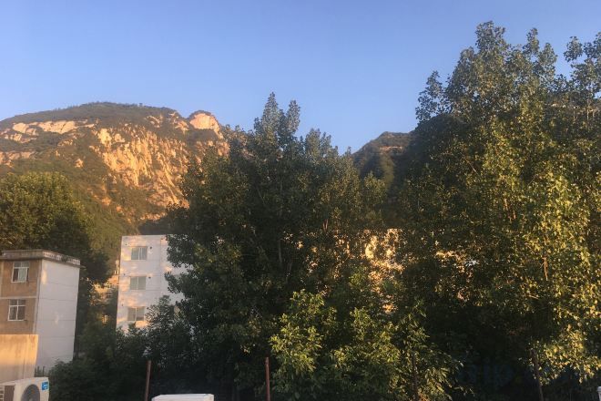 Paisaje montañoso con edificios y árboles.