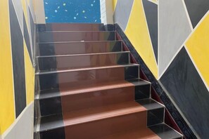 A staircase with alternating black and brown steps, surrounded by walls with geometric patterns.