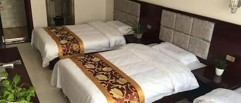 Habitación de hotel con dos camas, un escritorio y una planta en maceta.