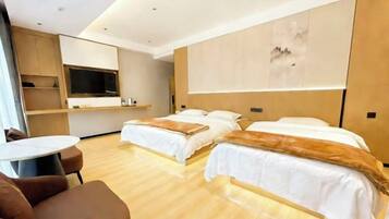 A modern hotel room with two beds, a TV, a small table, and a sofa.