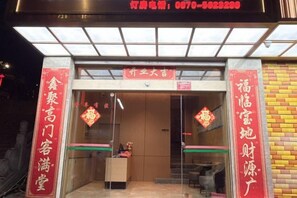 L’entrée d’un hôtel, avec un comptoir de réception, une porte vitrée et une enseigne au-dessus de la porte.