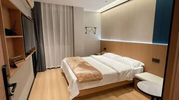 A hotel room with a bed, bedside table, and built-in TV.