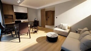 Una sala moderna con sofá, reposapiés, mesa de comedor, sillas y televisor.