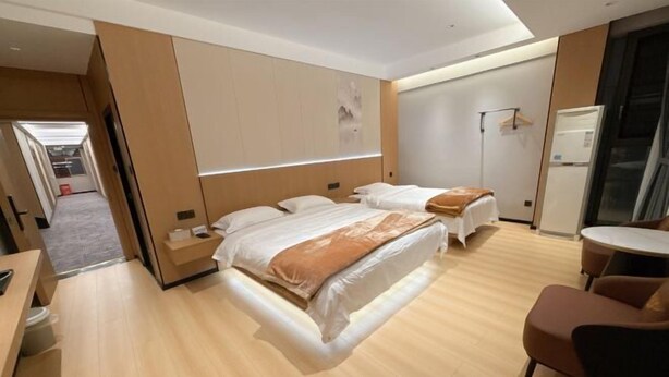 Una habitación de hotel con dos camas, una mesita, una silla y un refrigerador.