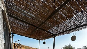 An outdoor wooden deck with a table and chairs, a hanging chair, and a hanging planter. - Vacation homes Trinacria (Sicilia)