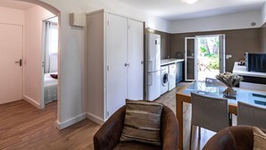 Ett kompakt bostadsutrymme med ett litet kök, en matplats och ett separat sovrum.