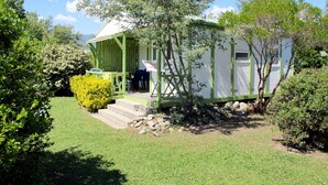 Une petite maison de plain-pied avec une véranda verte et un petit jardin.
