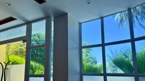 Een kamer met grote ramen, een plafond met ingebouwde verlichting en uitzicht op groen.