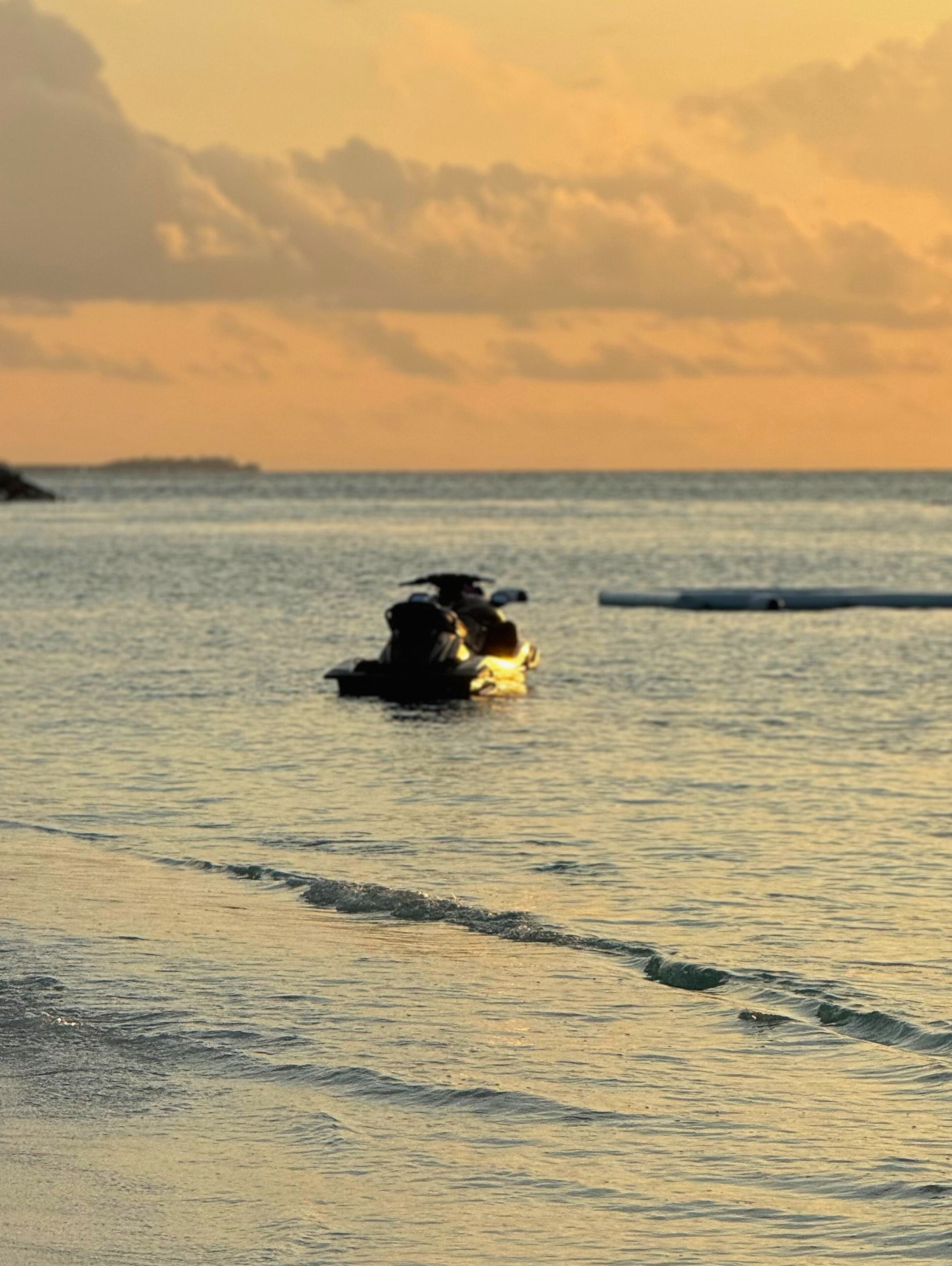 A beach scene with a person in the water, waves, and a distant landmass.