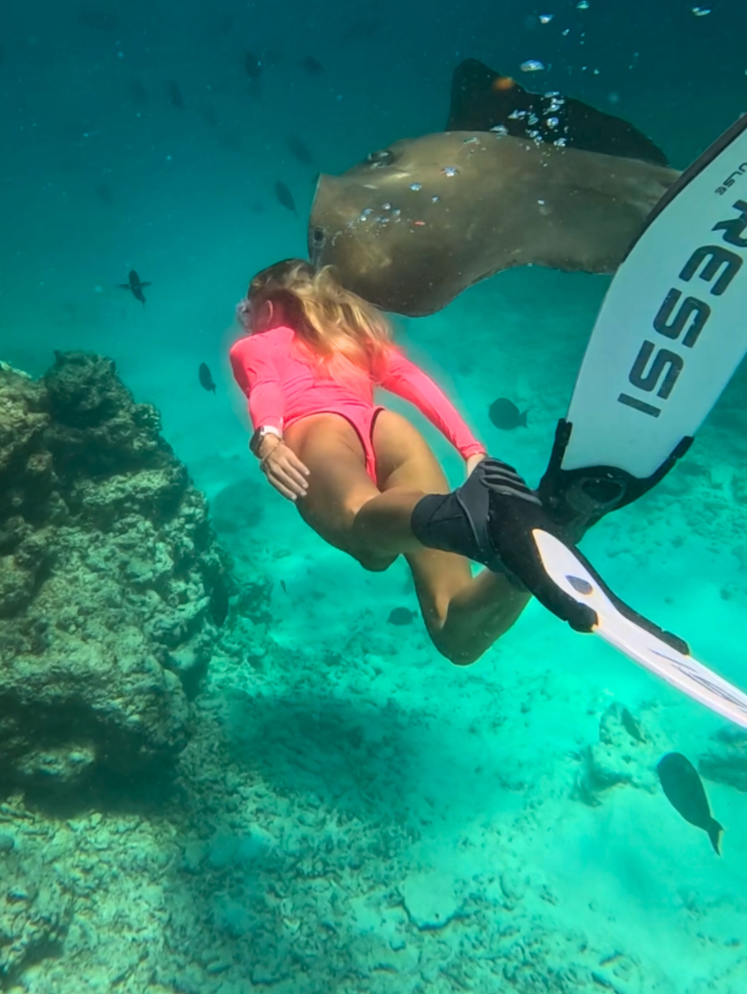 A diver in a pink swimsuit underwater with a snorkel and fins.