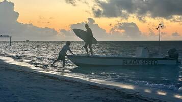Un bote llamado BLACK SPEED en una playa con un atardecer de fondo.