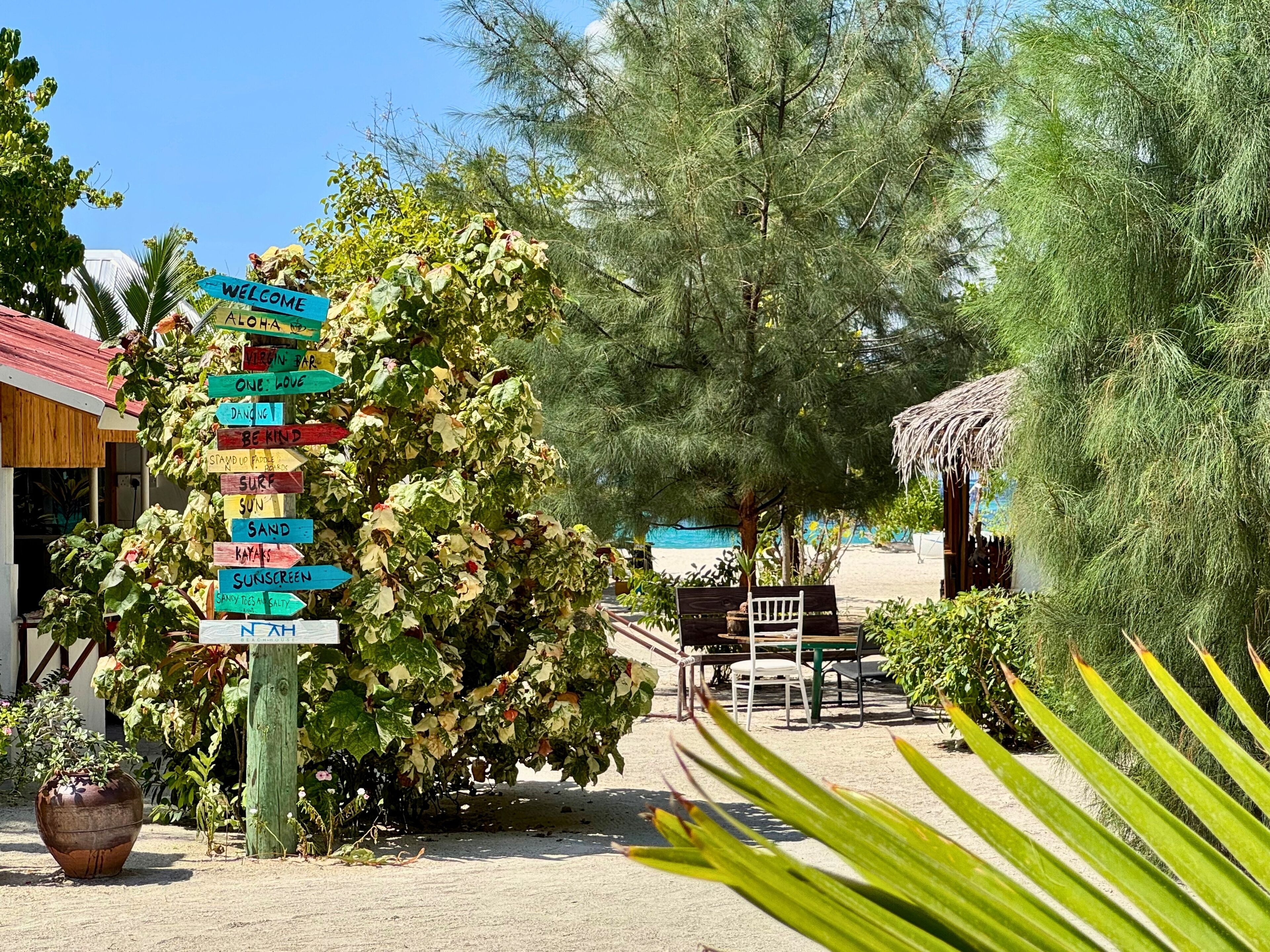 A tropical resort with a signpost listing activities like surfing and snorkeling.