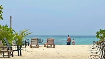 Praia particular, areia branca, espreguiçadeiras, guarda-sóis