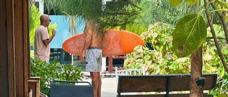 A wooden bench and a hammock in a lush garden with a large umbrella.