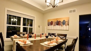Comedor con una gran mesa dispuesta para seis personas, velas y un adorno en la pared.