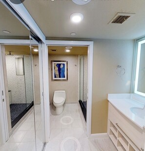 Bathroom features a glass-enclosed shower, white toilet, and sink with a mirror.