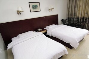 A hotel room with two single beds, a wooden headboard, a nightstand, a telephone, two wall-mounted lamps, and a chair. - Xing'an Hongfu Business Hotel (Xing'an County)