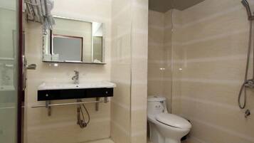 A bathroom with a sink, mirror, toilet, and shower.