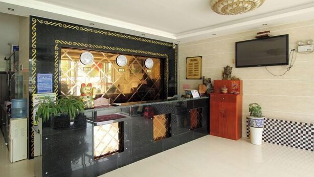 A reception area with a black counter, a glass display case, a television mounted on the wall, and a checkered floor pattern. - Xing'an Hongfu Business Hotel (Xing'an County)