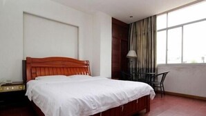 Un dormitorio con una cama de madera, una mesita de noche, una silla y un amplio ventanal con cortinas.