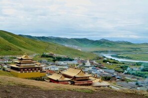 Un edificio tradicional con varios tejados, un río al fondo y un paisaje montañoso.