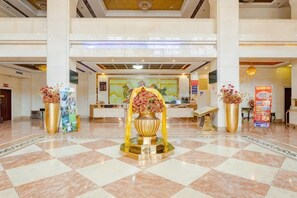 A hotel lobby with a check-in counter, reception desk, and decorative vases.