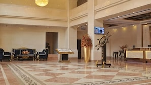 Un vestíbulo de hotel con mostrador de recepción, zona de estar y una araña.