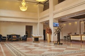A hotel lobby with a check-in counter, seating area, and a chandelier.