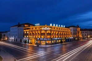 A historic building with illuminated signage, a central entrance, and a street view. - Zoige Grand Hotel (Zoige County People's Government) (Zoige)