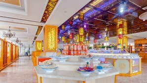 Un vestíbulo de hotel con una zona de bar central, faroles decorativos y suelo de mármol.