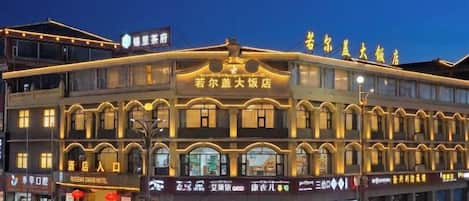 A multi-story hotel with a traditional architectural style, featuring multiple storefronts on the ground level.