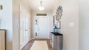 Un couloir doté d’un plancher en bois, d ’un tapis blanc, d’une porte portant l’inscription « BELCASTRO » et d’un élément décoratif mural.